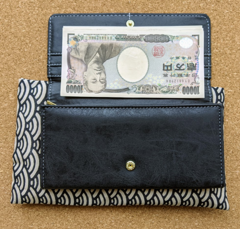 新札21万円を下向きに揃えて財布に入れる